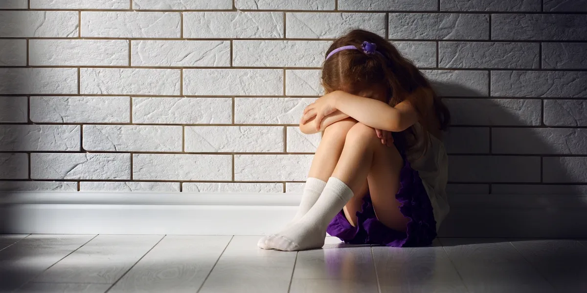 A little girl sitting on the floor with her head down.