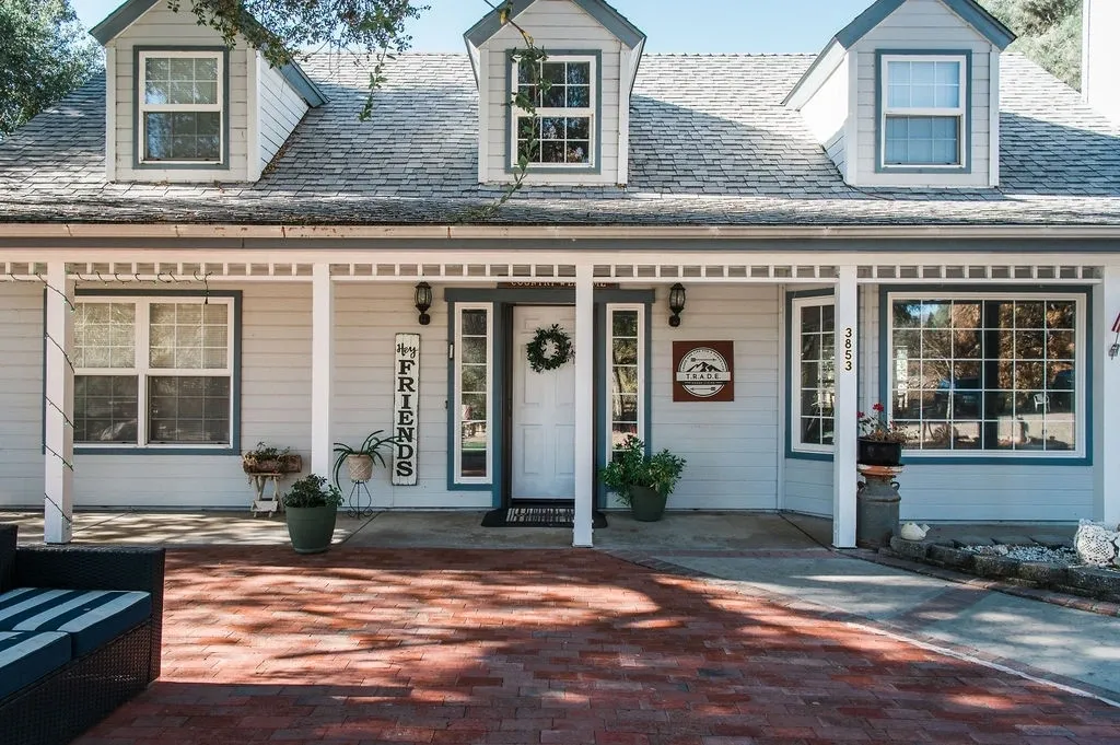 A white house with red brick driveway and front porch.