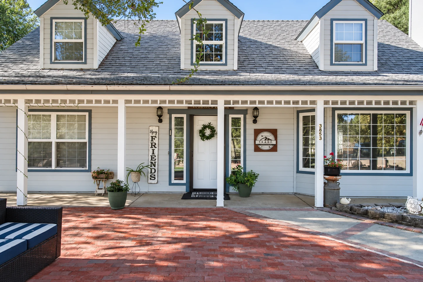 A white house with red brick driveway and front porch.