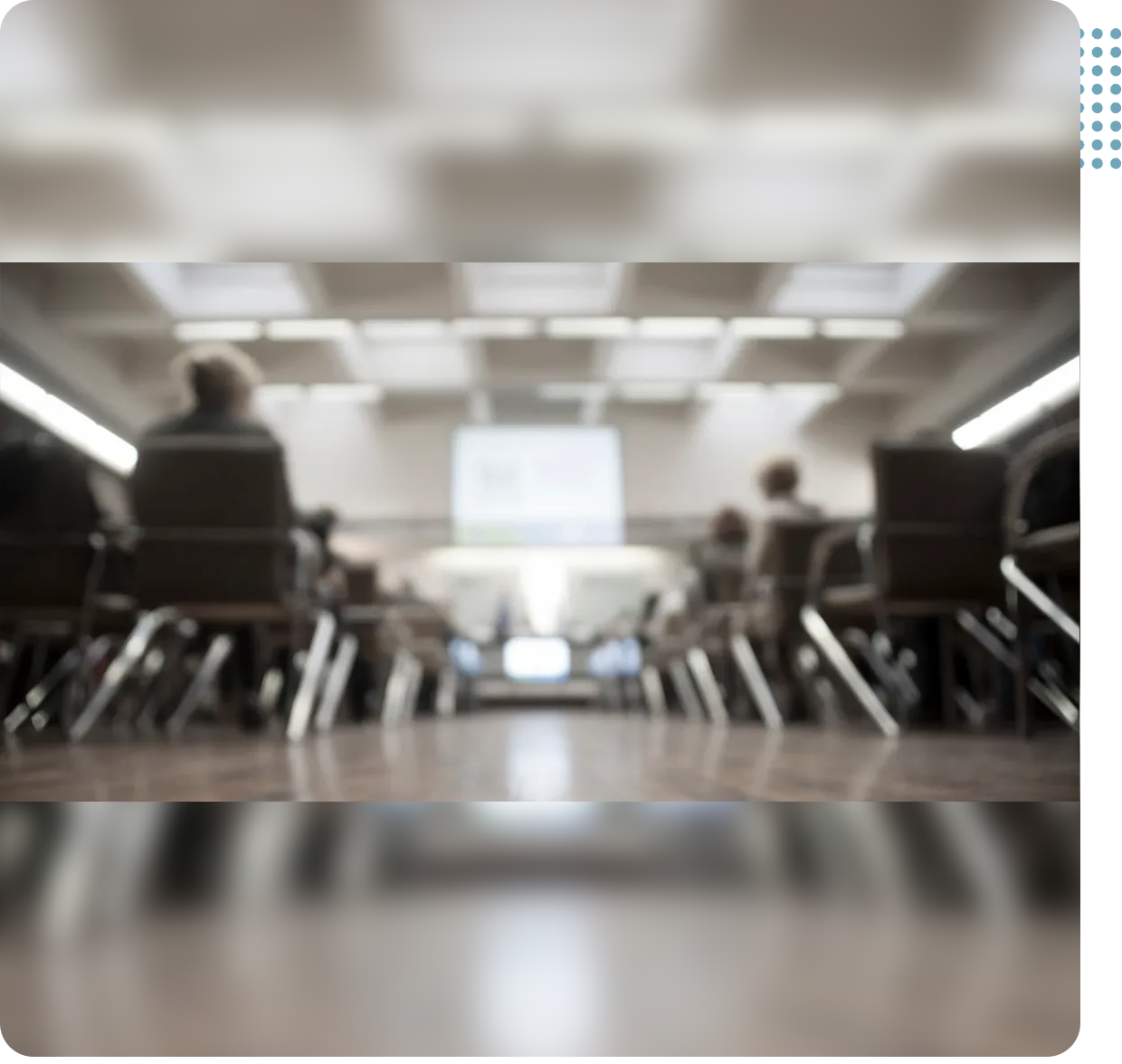 A blurry photo of people sitting in chairs at a meeting.